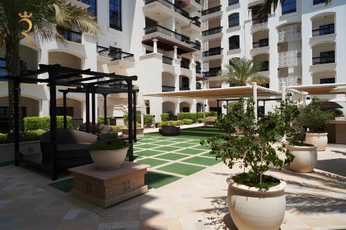 a courtyard of a building with potted trees in a courtyard at Elegant 2BR Golf View Oasis in Yas Island - Maids Room, Pool & Near Yas Mall in Yas Island