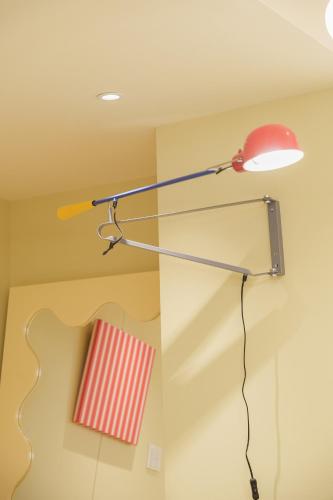 a lamp hanging from a ceiling with a red chair at 寅ホテル 御徒町 TORA HOTEL Okachimachi in Tokyo