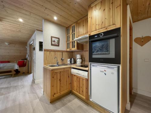 une cuisine avec des armoires en bois, un évier et un réfrigérateur dans l'établissement ARA15 Appartement 6 Pers centre station Carroz, aux Carroz d'Arâches