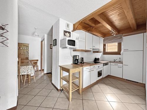une cuisine avec des armoires blanches et une table à l'intérieur dans l'établissement SC316 - Duplex 8 Pers centre des Carroz, aux Carroz d'Arâches