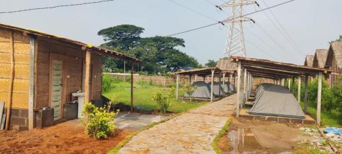 a row of small buildings in a field with trees at Hill Stone View Hampi in Hampi