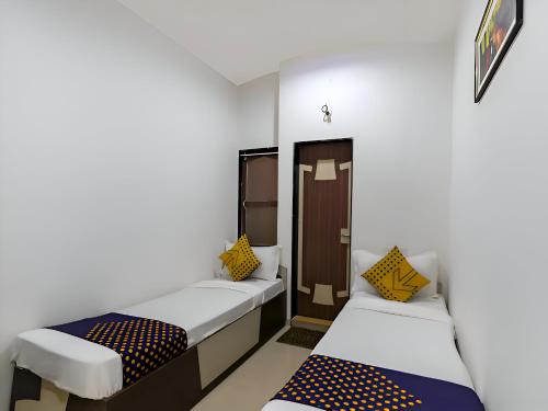 a room with two beds and a door at Hotel Atithi - Oposite Shreeji Hospital in Rajkot