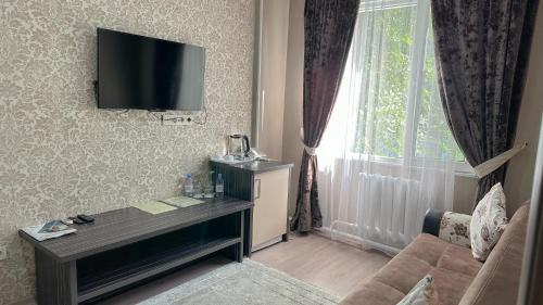 a living room with a television on a wall with a window at Resident Hotel Almaty in Almaty