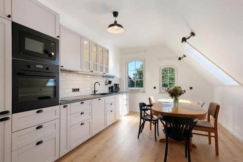 a kitchen with white cabinets and a table with chairs at Ferienwohnungen Stolzenhagener 7 in Lunow