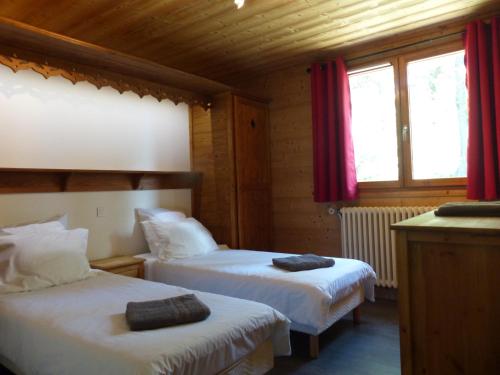 une chambre avec deux lits avec des rideaux rouges dans l'établissement Appartement dans un chalet typique de montagne à La Rosière, à Montvalezan