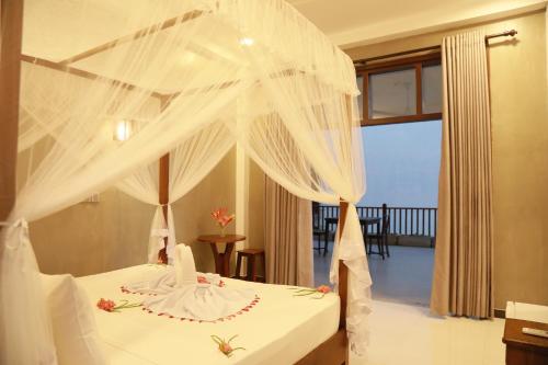 a bedroom with a bed with white mosquito net at Gold Bubble in Ahangama
