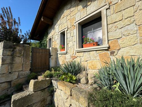 a stone house with two windows with potted plants at Kamenny apartman in Libunec