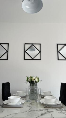 a dining room table with plates and a vase of flowers at Hemel Apartments - Serenity Suite in Hemel Hempstead