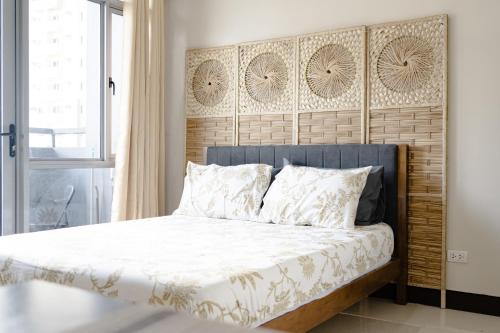 a bedroom with a bed with a wooden headboard at Cubao Manhattan Heights Residential Condo TC10N - Bright Studio with Pool, Balcony - Next to AliMall and SM - Walking Distance to Araneta Coliseum and Gateway Mall in Cubao Quezon City - Staycations by SMS in Manila