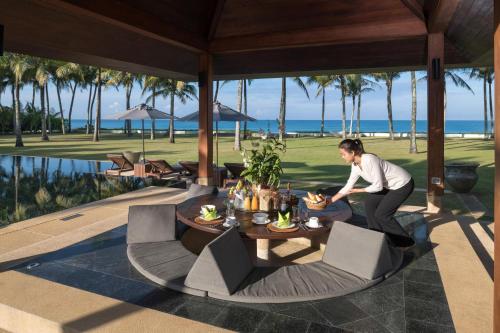 a woman sitting at a table in a resort at Villa Ananda at Jivana Beach Villas in Pilai Beach