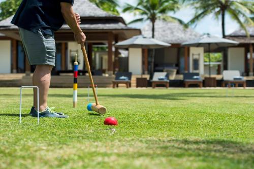 a man playing a game of tball in a yard at Villa Ananda at Jivana Beach Villas in Pilai Beach