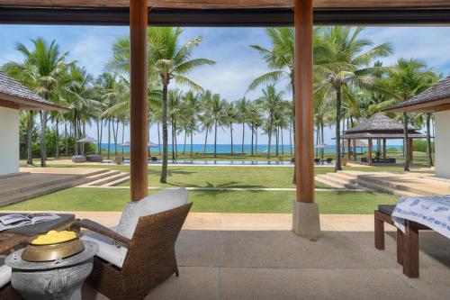 a patio with a view of the ocean and palm trees at Villa Ananda at Jivana Beach Villas in Pilai Beach