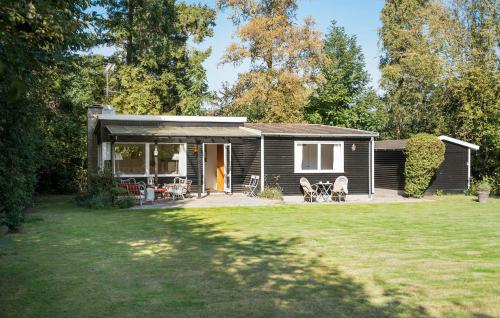a small cabin with a porch and chairs in a yard at 2 Bedroom Lovely Home In Dronningmølle in Dronningmølle