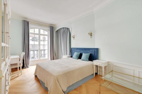 - une chambre blanche avec un lit bleu et une fenêtre dans l'établissement Trocadero - Longchamp 2bdr, à Paris