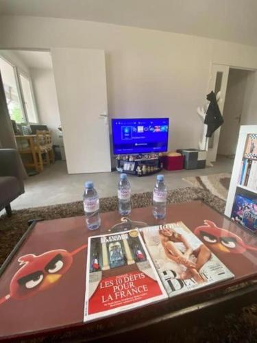 - une table basse avec un magazine et 2 bouteilles d'eau dans l'établissement Cosy appart à balcon Tour Eiffel et parking, à Paris