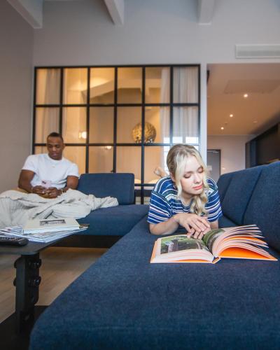 a young girl laying on a couch reading a book at Unity Tampere - A Studio Hotel in Tampere