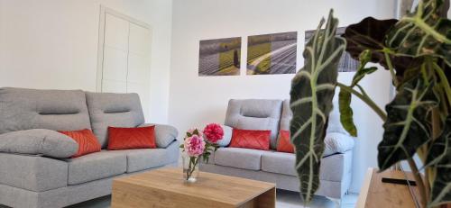 a living room with two couches and a table with flowers at Apartamentos Arenal in Jerez de la Frontera