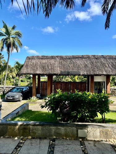 a house with a thatch roof and a car parked at Luxury Apartment on the Beach in Belle Mare