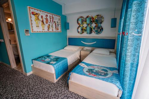 two beds in a room with blue walls at Leman Otel in Denizli
