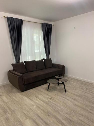 a living room with a brown couch in front of a window at Apartament satina in Craiova