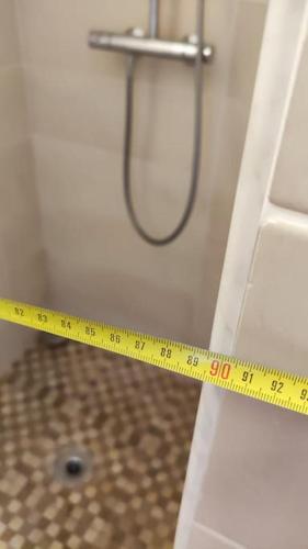 a yellow measuring tape on a bathroom door with a shower at Appartement de 51 m2 avec jardin de 51 m2, parking privé in Achères