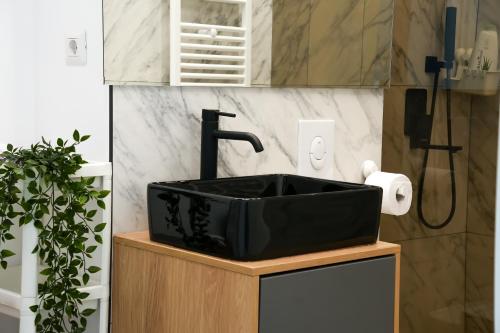 a black sink on a wooden stand in a bathroom at Sara - Stylish Apt with Balcony near Piata Obor in Bucharest