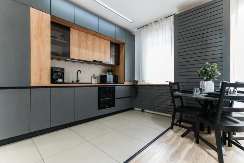 a kitchen with a table and chairs and a kitchen with black cabinets at Sara - Stylish Apt with Balcony near Piata Obor in Bucharest