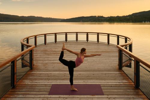 a woman doing a yoga pose on a dock at MOLO LIPNO RESIDENCE in Lipno nad Vltavou