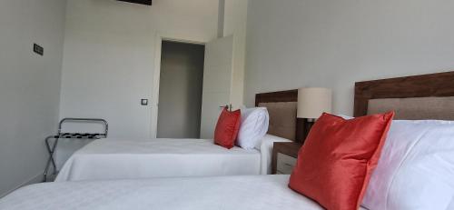a hotel room with two beds with red pillows at Apartamentos Arenal in Jerez de la Frontera