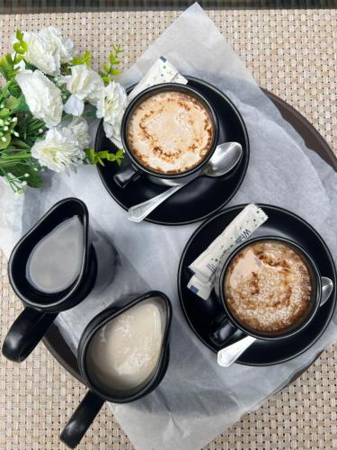 three cups of coffee sitting on a table with flowers at Burj Ul Zaki in Islamabad