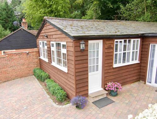 a small shed with white doors and windows at The Little Lodge House in Ayot Saint Peter