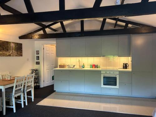 a kitchen with white cabinets and a table and a dining room at The Little Lodge House in Ayot Saint Peter