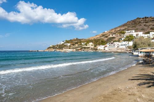 a beach with white houses on a hill next to the ocean at Sunset Realty Apartment in Ano Syros