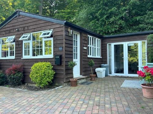 a small house with a brick patio in front of it at The Little Lodge House in Ayot Saint Peter