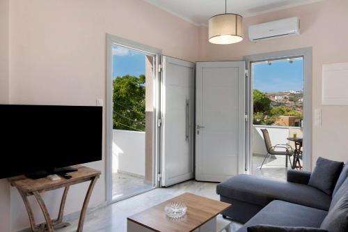 a living room with a couch and a tv at Sunset Realty Apartment in Ano Syros