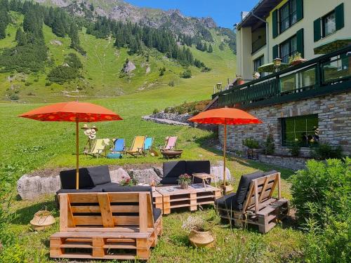 a patio with chairs and umbrellas in front of a building at Arlberg Stuben - das kleine, feine Hotel in Stuben am Arlberg