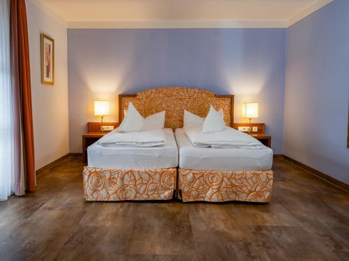a bedroom with two beds and two lamps at Hotel Geiger in Füssen
