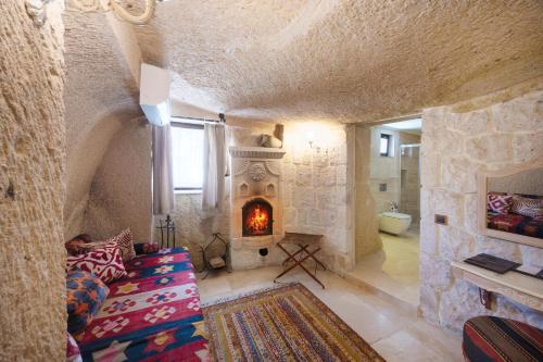 a living room with a fireplace in a stone wall at Tafoni Houses Cave Hotel in Ortahisar