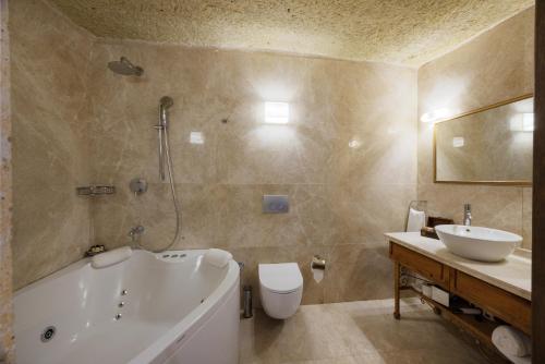 a bathroom with a tub and a toilet and a sink at Tafoni Houses Cave Hotel in Ortahisar