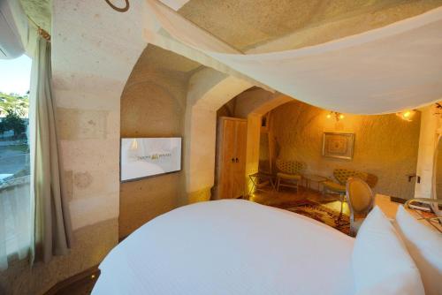a bedroom with a bed and a living room at Tafoni Houses Cave Hotel in Ortahisar