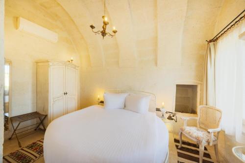 a bedroom with a white bed and a chandelier at Tafoni Houses Cave Hotel in Ortahisar