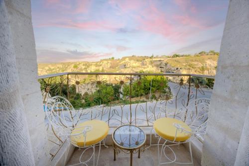 a balcony with two tables and chairs and a view at Tafoni Houses Cave Hotel in Ortahisar