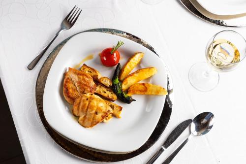 a plate of food with chicken and vegetables on a table at Tafoni Houses Cave Hotel in Ortahisar