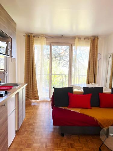 un salon avec un canapé rouge dans une cuisine dans l'établissement Charmant logement situé en plein verdure et au centre ville de Rosny Sous Bois, à Rosny-sous-Bois