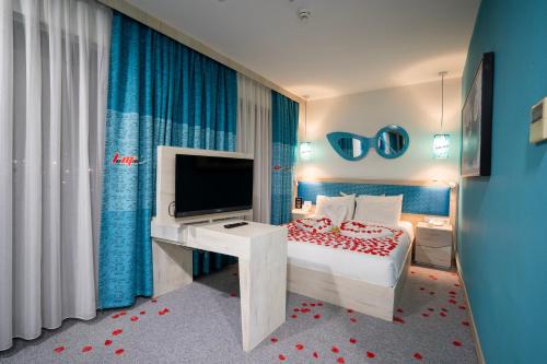 a bedroom with a bed with a television and a desk at Leman Otel in Denizli