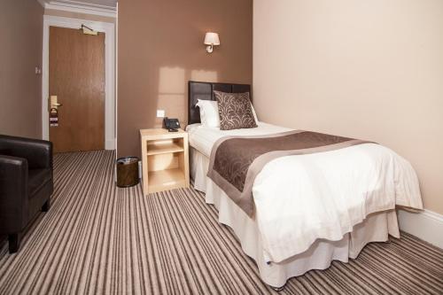 ein Hotelzimmer mit einem Bett und einem Stuhl in der Unterkunft Burnett Arms Hotel in Banchory