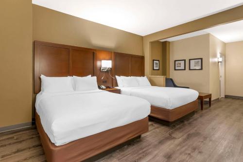 two beds in a hotel room with white sheets at Comfort Suites At the University in Conway