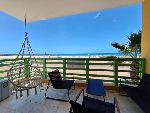 a porch with chairs and a swing overlooking the beach at Ca Luna Deluxe sun & Beach in Sal Rei