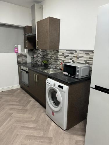 a kitchen with a washing machine and a microwave at 1 bedroom kitchen Flat in Nottingham