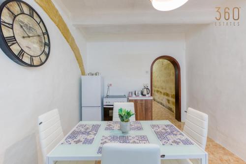a dining room with a table and a clock on the wall at Authentic Townhouse with backyard in Sliema by 360 Estates in Sliema